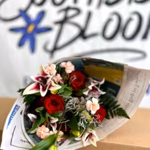 Flower bouquet with red roses, pink lilies, and greenery wrapped in newspaper