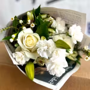 A small bouquet of white roses and flowers wrapped in newspaper