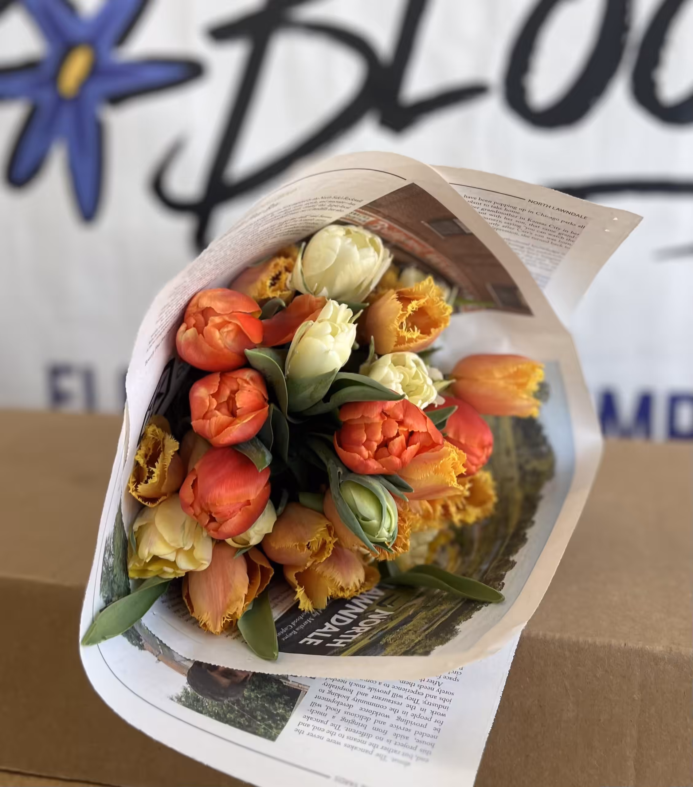 IMG_1441 Bouquet of orange, yellow, and cream tulips wrapped in newspaper