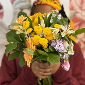 A person in a red sweater holds a colorful bouquet